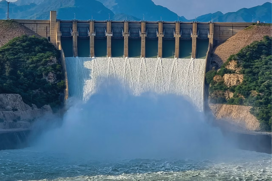 Dam spillway releasing water between hills